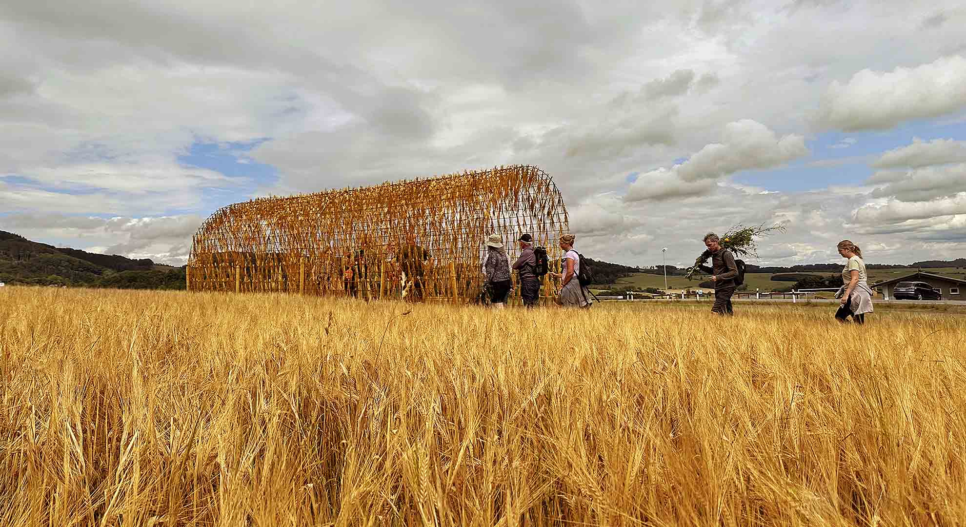 Estructura de materiales naturales en un campo de cereales, que integra arquitectura y sostenibilidad en el paisaje rural.