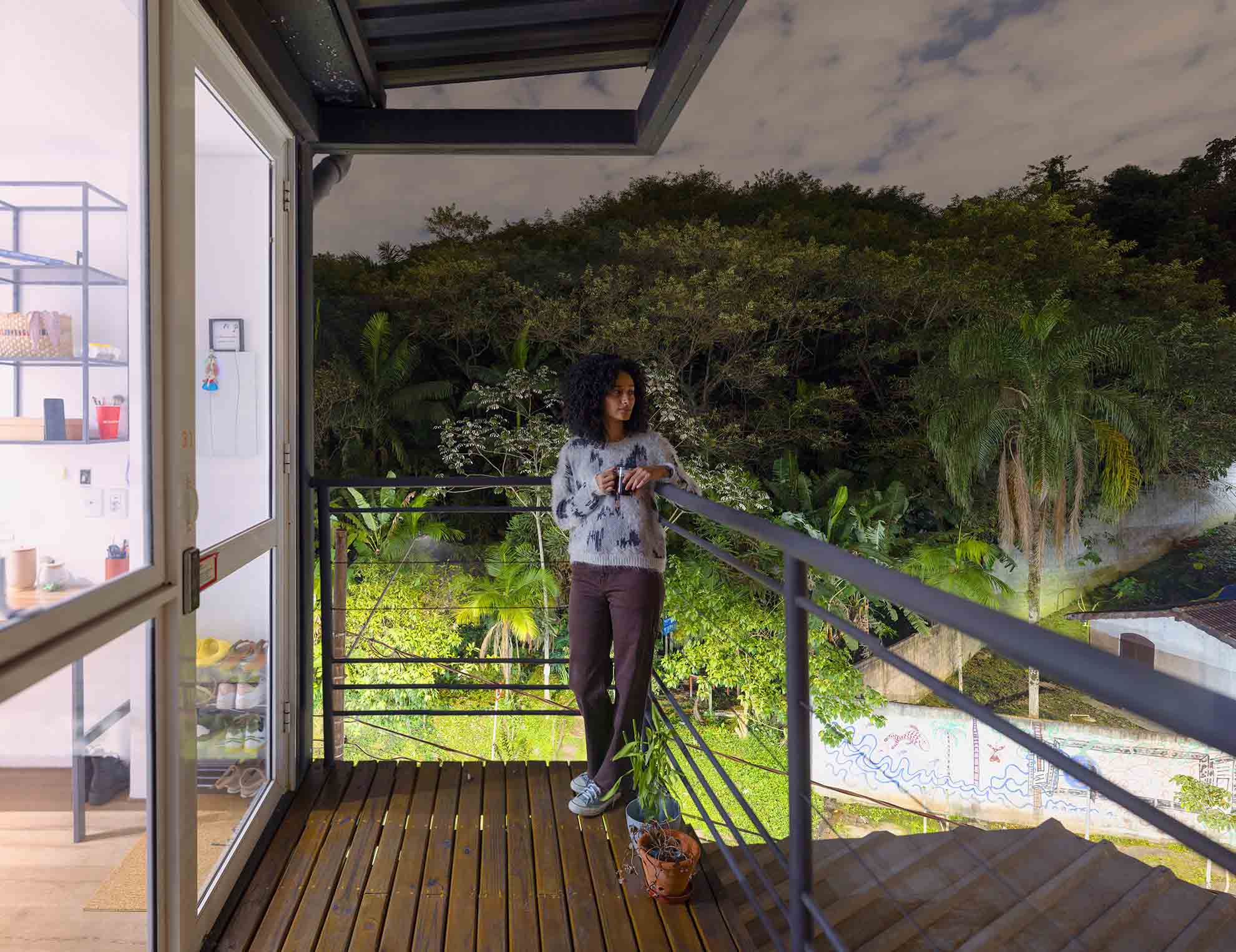 Resident on balcony of a dignified housing unit surrounded by greenery