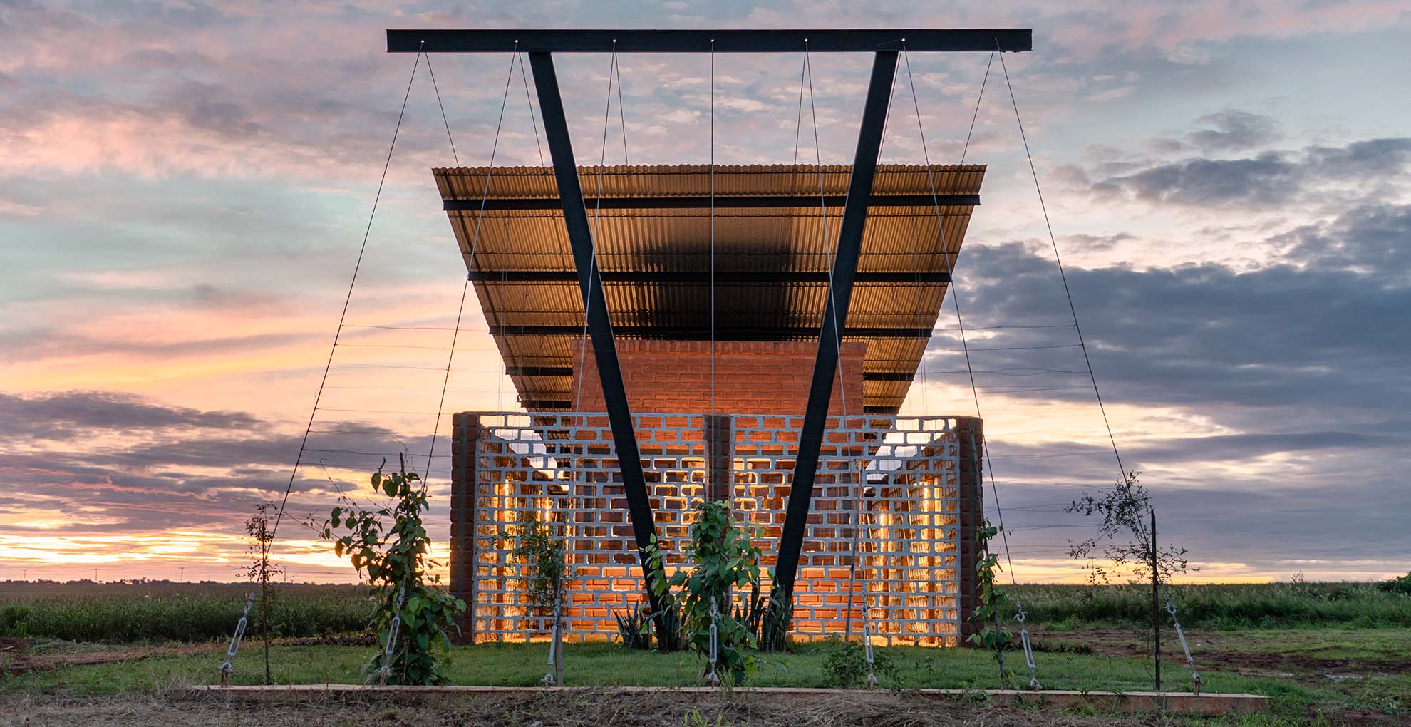 Vista frontal de la Oficina Nordeste Curuguaty al atardecer, un proyecto que apuesta por la reutilización de materiales locales en su construcción.