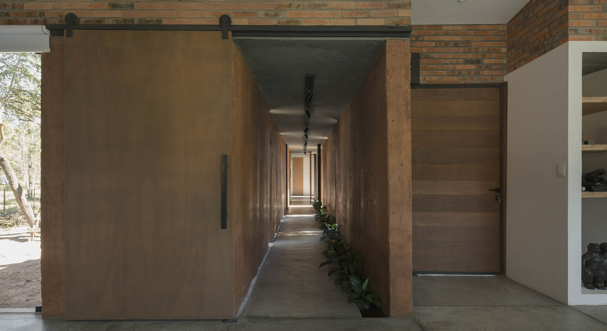 Pasillo interior de la Vivienda Luce y Pablo, construido con técnicas de reutilización de tierra y diseño eficiente de espacios.