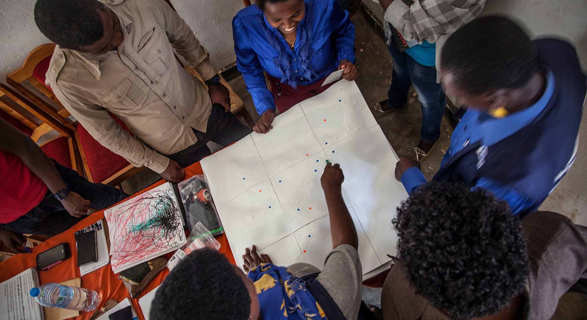 Una sesión participativa de diseño de mejoras vecinales en el campo de refugiados de Kiziba, Ruanda, en septiembre de 2017, utilizando un modelo impreso en 3D desarrollado con imágenes de satélite y el software Maya. Foto © Joan Amorós Elorduy